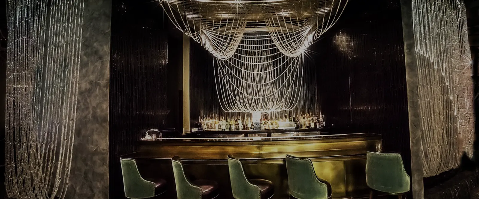 A dimly lit casino lounge with a brass bar and chandelier